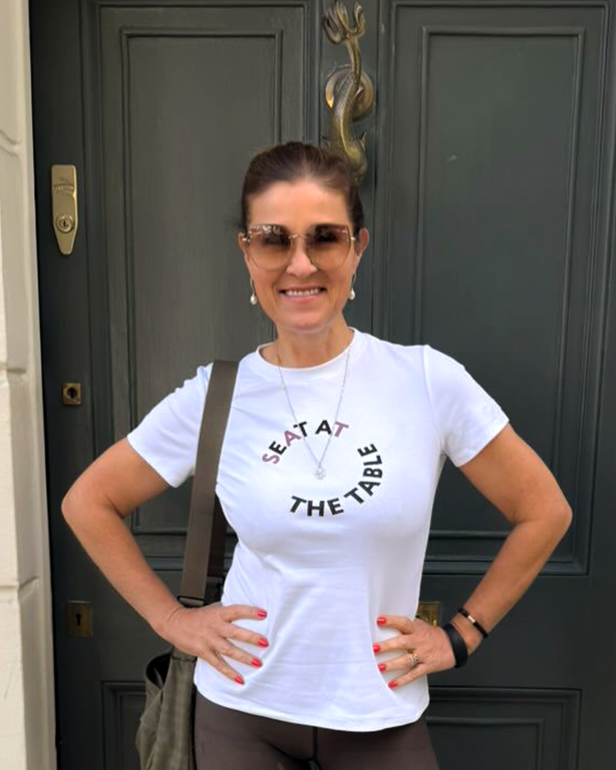 Woman wearing a white t-shirt with text standing in front of a door.