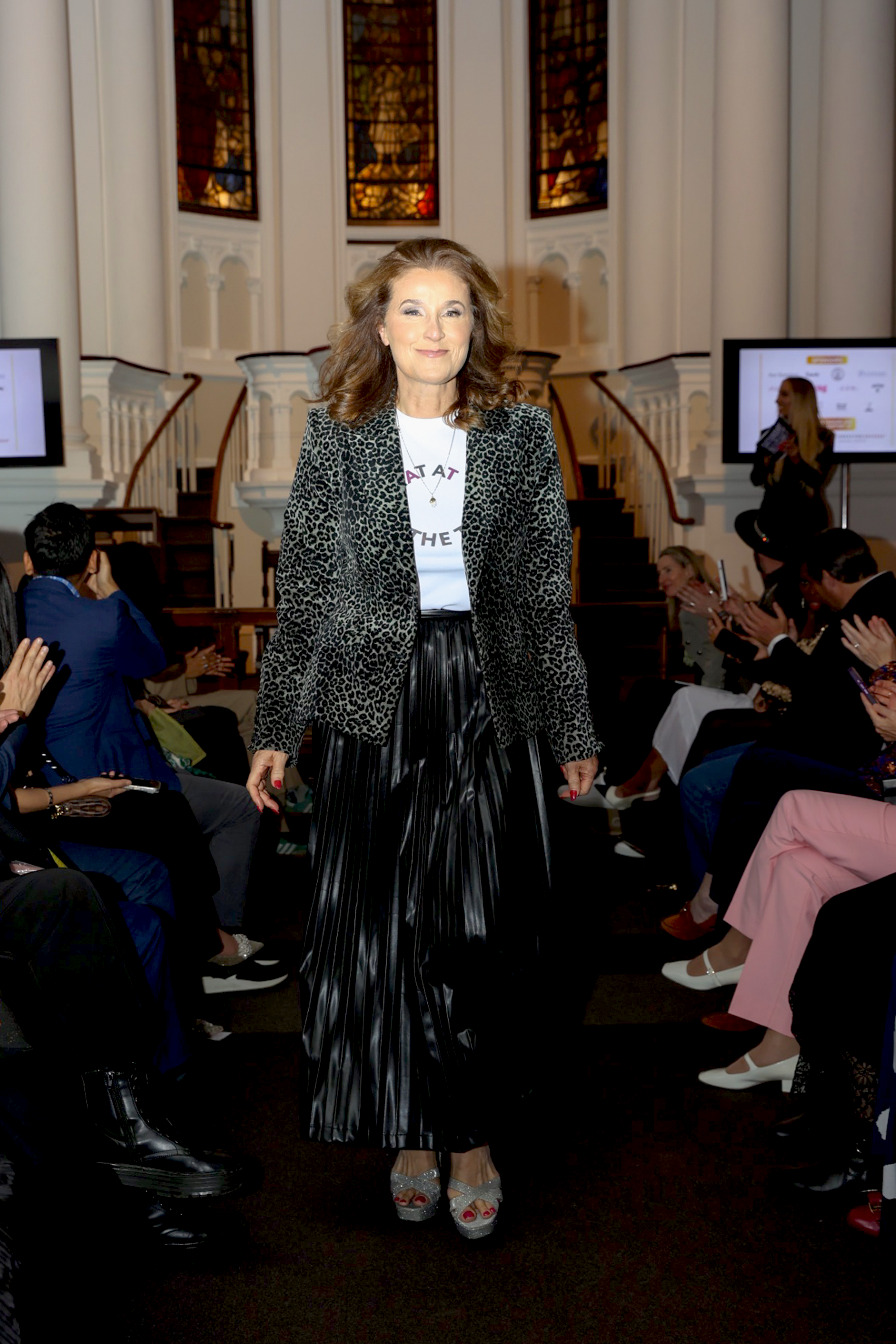 Woman in a stylish outfit standing in an indoor setting with people around